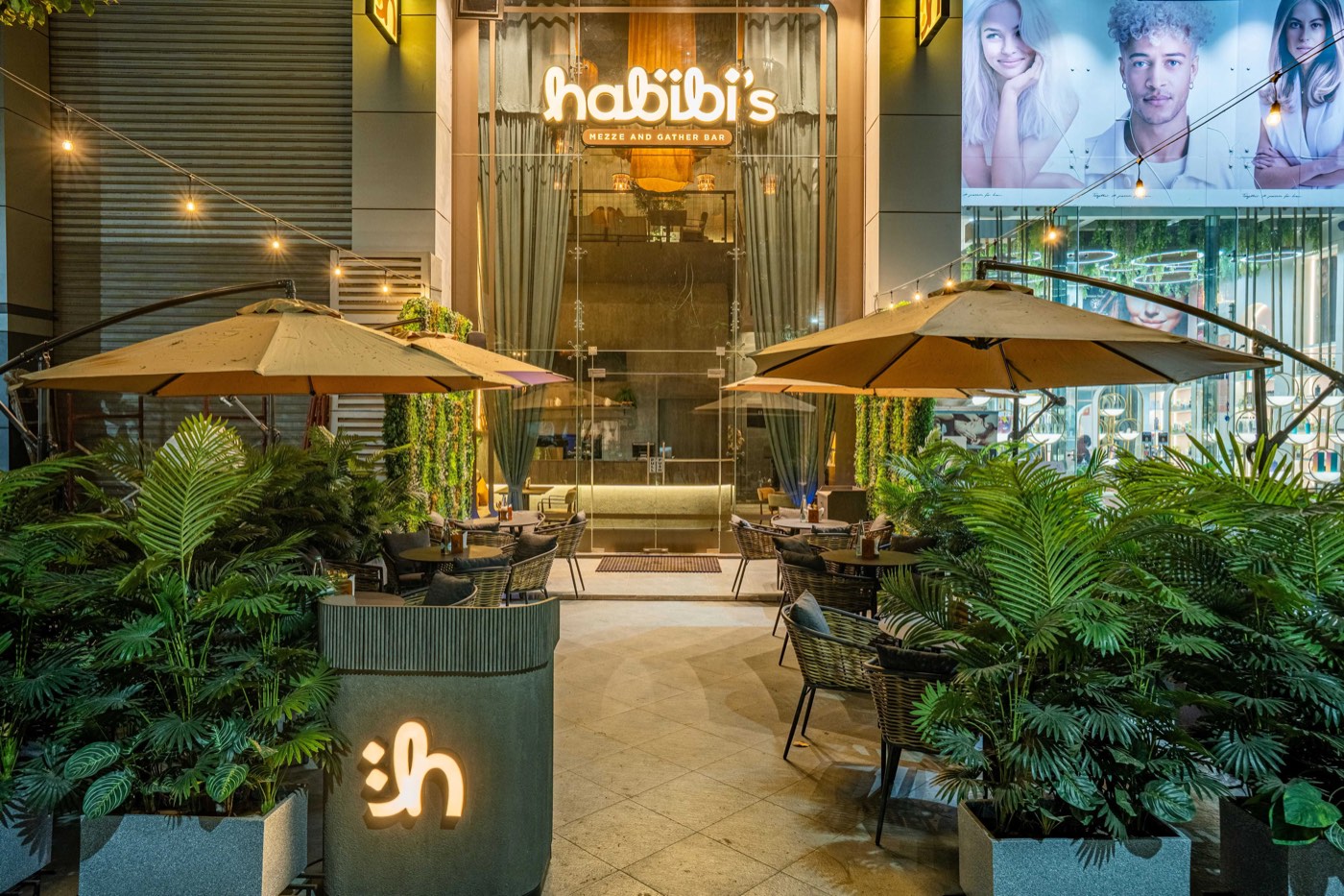 Habibi's terrace at night, with the lit wordmark and outdoor seating