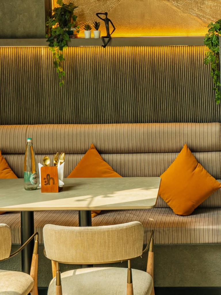 Lounge seating with warm light, plants and orange cushions